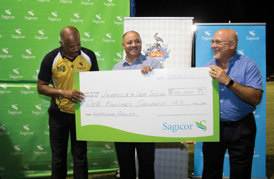 Vice-Chancellor, Professor Sir Hilary Beckles (left) is presented with a cheque for US$100,000 by Mr Donald Austin, Chief Executive Officer, Sagicor Life Eastern Caribbean, (centre) and Mr Brenton Hilaire, Agency Manager, Sagicor Life, Dominica (right) during the post- match presentation. The money will go towards rebuilding schools and hospitals across Caribbean islands impacted by hurricanes Irma and Maria earlier this year.